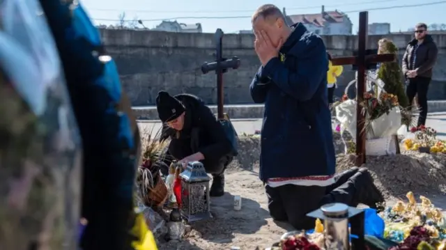 Mourners by a soldier's grave in Lviv, Ukraine