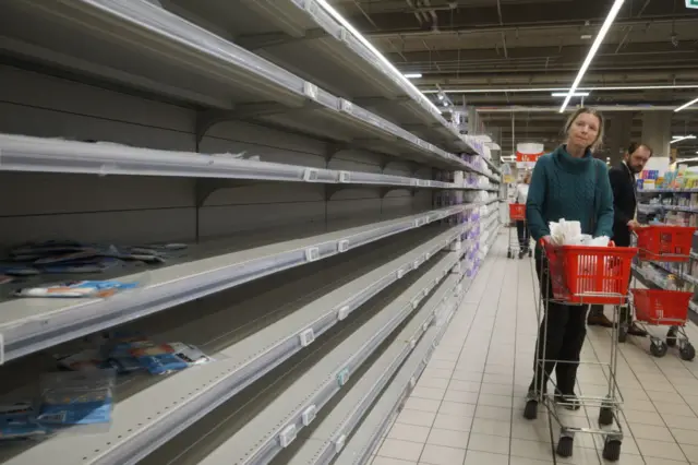 A woman looks at empty shelves at a shopping mall in Moscow, Russia, 16 March 2022