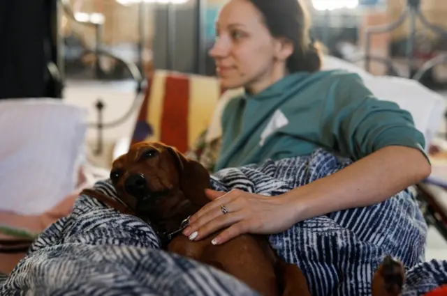 A woman fleeing Russia's invasion of Ukraine rests with a dog at a reception point in an old train station in Krakow