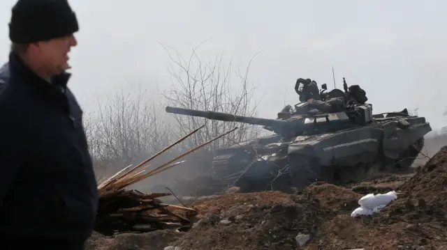 A man walking past a pro-Russian tank on the outskirts of the besieged city Mariupol