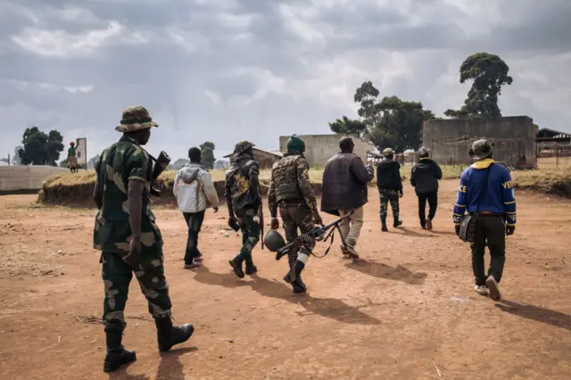 Commanders of the armed group Codeco walk through a village in Ituri