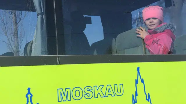 A child looks out of the window of a coach waiting to take Ukrainian refugees to Germany