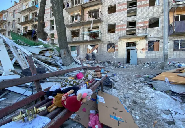 Municipal workers and volunteers remove debris of a damaged residential building in Kharkiv, 21 March 2022