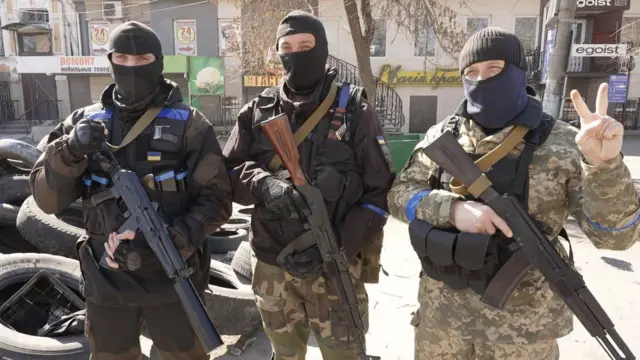 Three defenders of the farming town Voznesensk pose for the camera with their guns