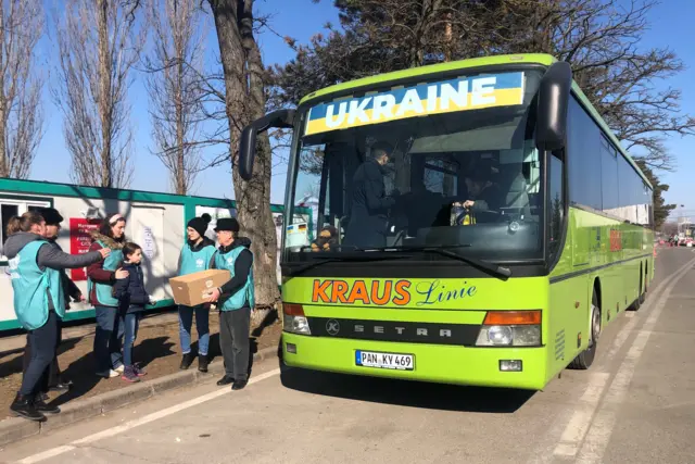 A green coach waiting to take Ukrainian refugees to Germany