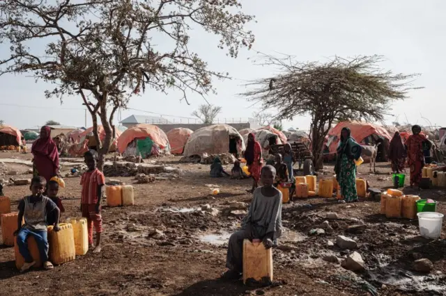 People wait for water with containers at a camp in Baidoa, Somalia, on February 13, 2022