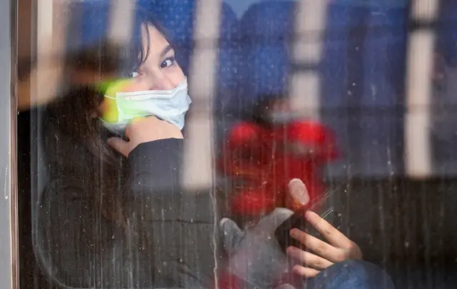 A refugee woman fleeing Russia's invasion of Ukraine looks on through a window before the train starts, on her way to Leipzig, at the central station in Goerlitz, Germany