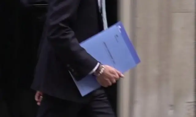 Rishi Sunak carrying two documents