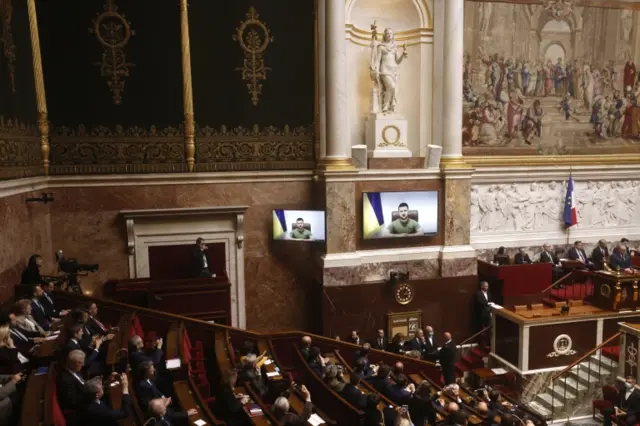 Volodymyr Zelensky (on screen) addresses French representatives during a video conference at the Nation Assembly in Paris, France, 23 March 2022.