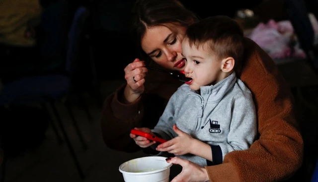 A mother feeds her child at a refugee shelter