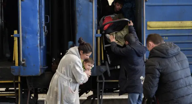 Family with buggy boarding train for Zaporizhzhia in Lviv