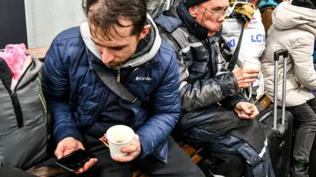 A refugee from Berdyansk checks his phone