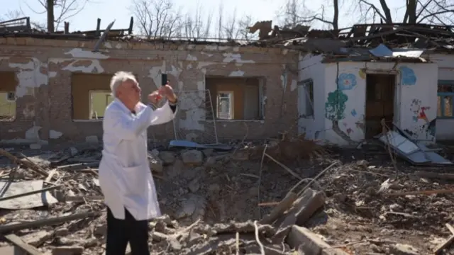 Doctor taking pictures outside damaged psychiatric hospital in Mykolaiv, 22 March 2022