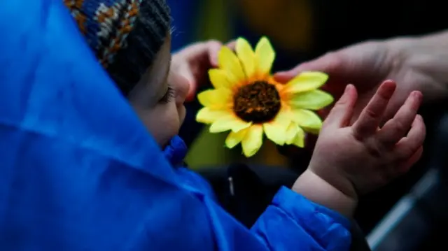 A baby holds a sunflower, a symbol of Ukraine, at a rally in New York on Wednesday