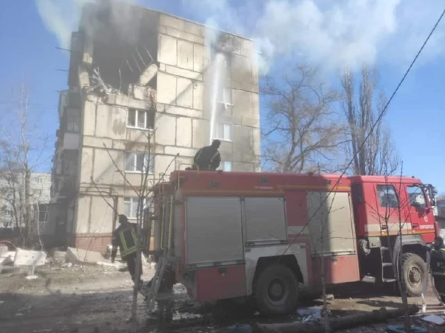 Firefighters on a truck outside a unit building damaged by Russian shelling