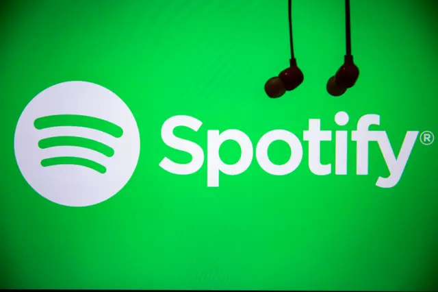 Spotify logo with two wired earbuds hanging nearby