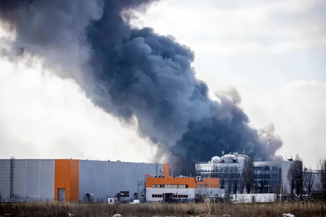 Photograph taken on 24 March 2022 shows smoke rising from a burning warehouse hit by a Russian shell in the suburbs of Kyiv