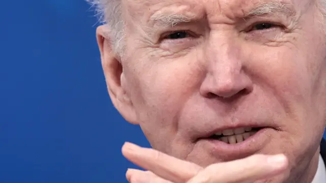 Joe Biden peers over intertwined fingers