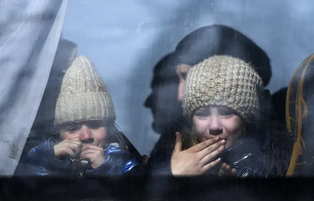 Little girls bid farewell as civilians are being evacuated along humanitarian corridors from the Ukrainian city of Mariupol under the control of Russian military and pro-Russian separatists, on March 24, 2022.