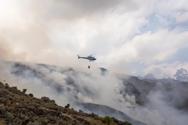 A helicopter dropping water on wildfires on Mount Kenya - March 2022