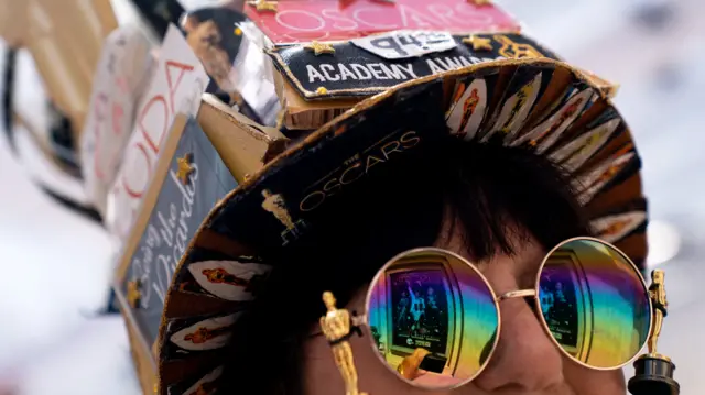 An awards fan wearing Oscars sunglasses