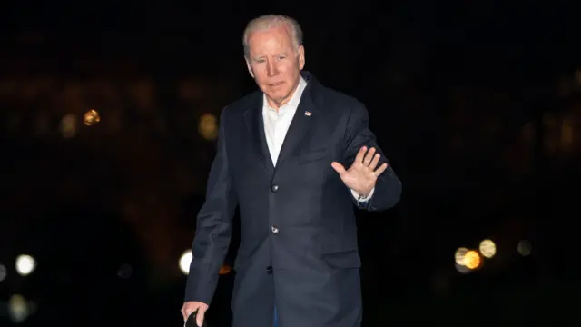 US President Joe Biden waving in the night outside the White House