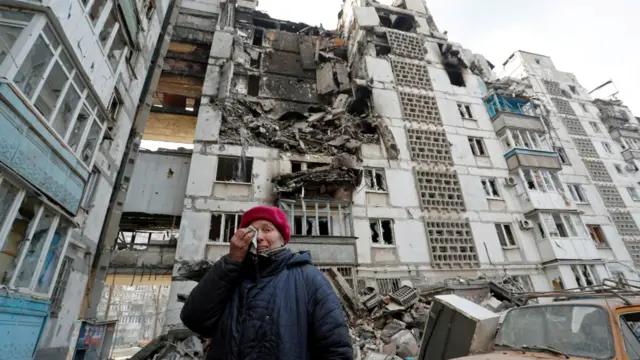 A local resident cries standing near her destroyed apartment in the besieged city of Mariupol