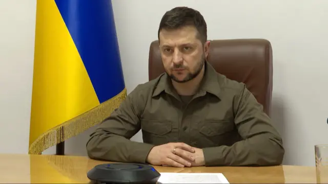 Ukrainian President Volodymyr Zelensky pictured at a desk in front of his country's flag