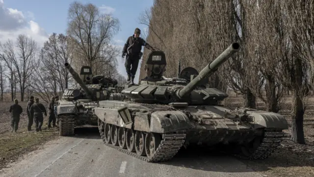 A Ukranian serviceman stands on top of a Russian tank captured after fighting outside Kyiv