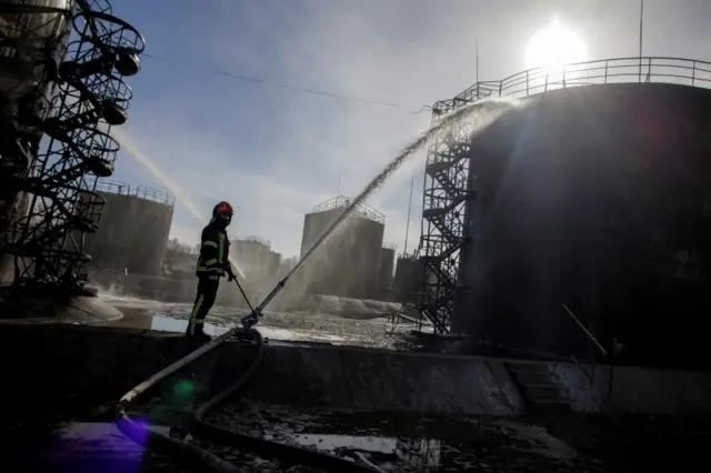 Firefighters continue to damp down the scene of an attack at the fuel storage facility in Lviv