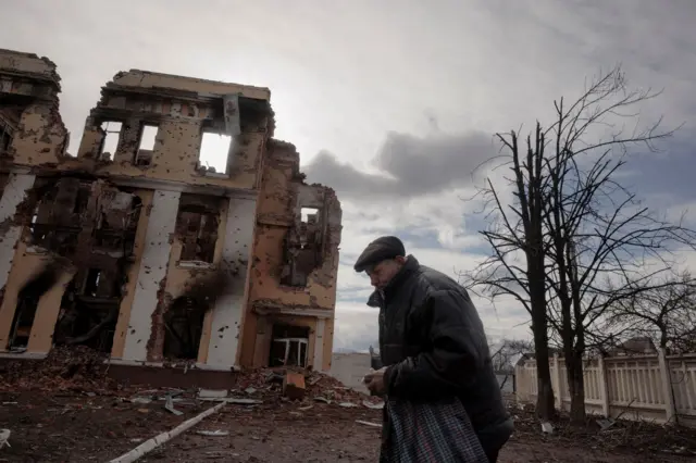 A man walks past a destroyed school building in Kharkiv