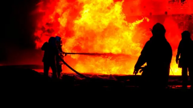 Firefighters weatring special protective clothing tackle the blaze at the fuel storage facility in Lviv after a missile strike