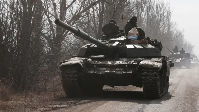 Pro-Russian troops in uniforms without insignia atop a tank outside Volnovakha