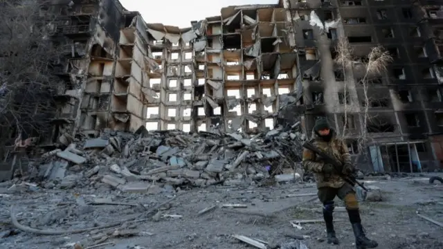 Russian soldier by destroyed apartment block in Mariupol, 28 March