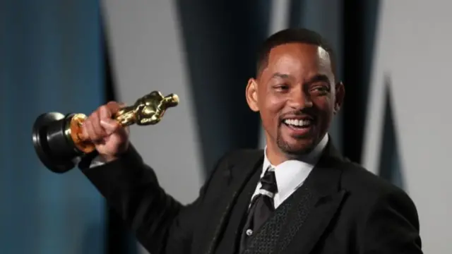 Will Smith smiles as he holds up his award at the Vanity Fair afterparty