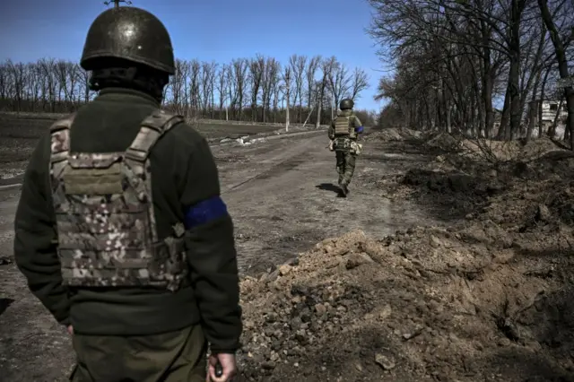 Ukranian servicemen walk in the village of Mala Rogan, east of Kharkiv, after the Ukranian troops retook the village