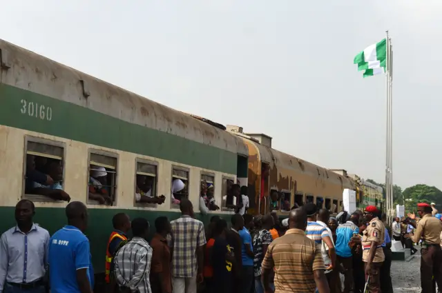 People wait beside a train at the Ebute-Metta headquarters of the Nigerian Railway Corporation in Lagos on March 7, 2017