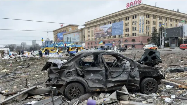 A burnt-out car in the square outside Kharkiv's city hall, which has been destroyed by Russian troop shelling