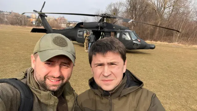 Ukrainian negotiator Davyd Arakhamia and his colleague in front of a helicopter in a field