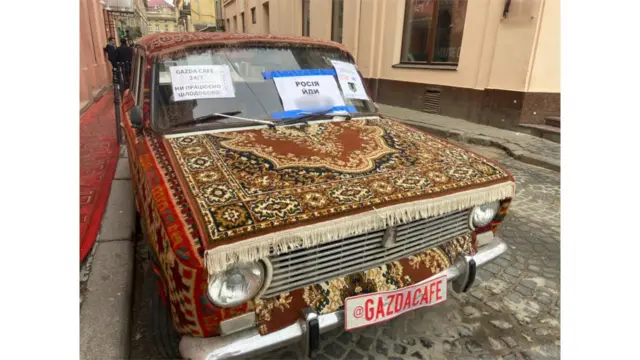 Car covered in carpets with printed signs on it