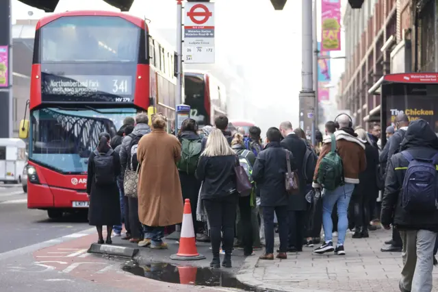 People attempt to board a bus at Waterloo station in London