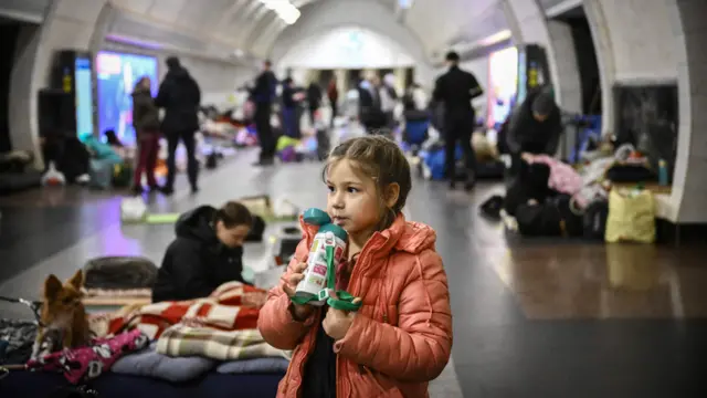 A girl drinks as she stands in an underground metro station used as bomb shelter in Kyiv