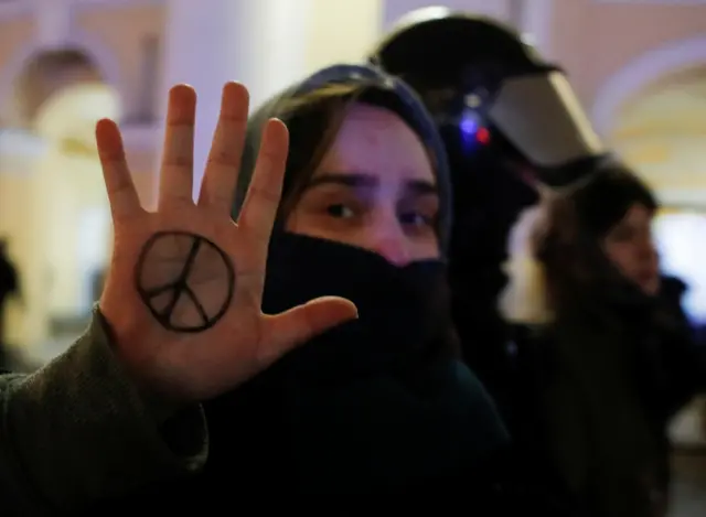 A demonstrator shows a peace symbol painted on her hand, next to a law enforcement officer, during an anti-war protest against Russia"s invasion of Ukraine, in Saint Petersburg, Russia March 2, 2022