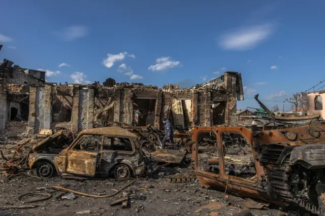 A Ukrainian rescue worker walks past destroyed Russian military vehicles as he looks for explosive items next to the railway station where the Russian forces were stationed, in the recaptured by the Ukrainian army Trostyanets town, in Sumy region, Ukraine, 29 March 2022