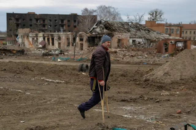 A local resident walks along a square damaged by shelling in the Ukrainian town of Trostyanets