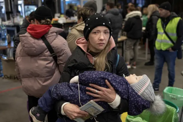 A woman cries as she holds her baby after they have arrived with other evacuees from Mariupol in the Ukrainian city of Zaporizhzhia