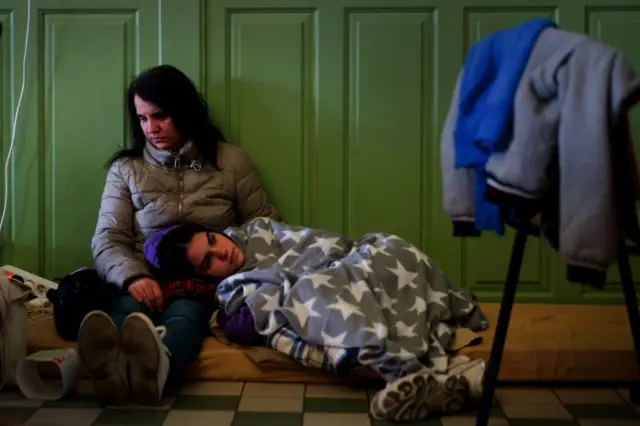 A Ukrainian woman and her child rest in a refuge room at Przemysl Glowny train station in Poland