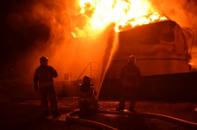 Rescuers at a fuel storage facility that was hit by suspected Russian cruise missiles in Ukraine's Rivne region