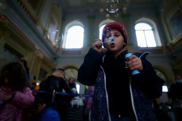 A young Ukrainian refugee blows bubbles in the entrance hall at Przemysl Glowny train station in Poland