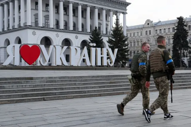 Ukraine's Territorial Defense Forces members pass next to a sign that reads "I love Ukraine", in Independence Square in Kyiv